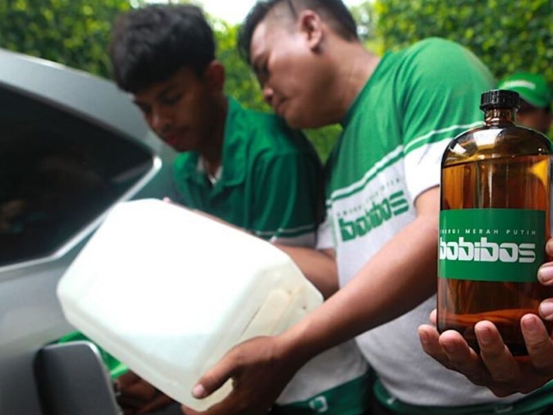 Tim Bobibos menuangkan bahan bakar dari jerami ke mobil sambil menunjukkan botol berlabel Bobibos sebagai energi alternatif buatan Indonesia.